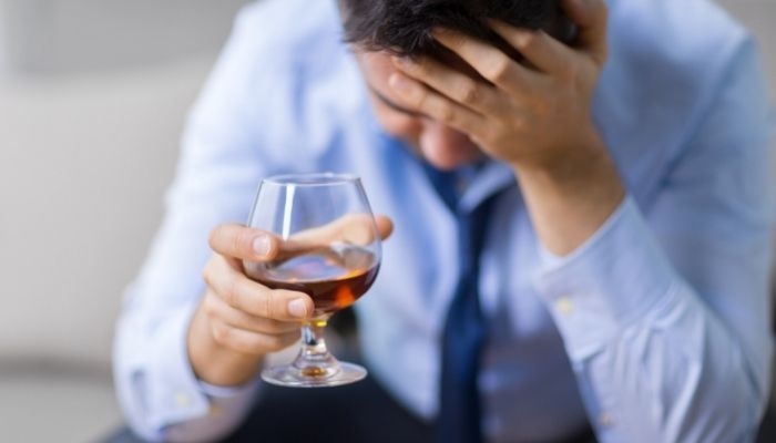 a man holding a glass of drink in his one hand and holding head with his other hand in stress
rem sleep disorder