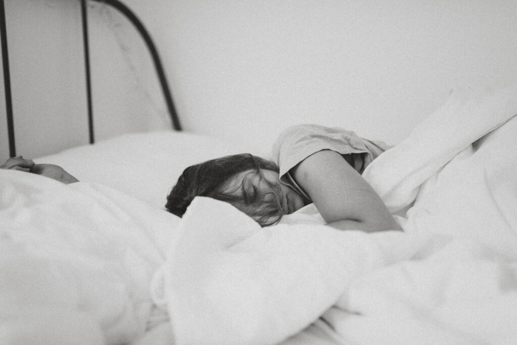 grayscale photo of sleeping woman lying on bed
