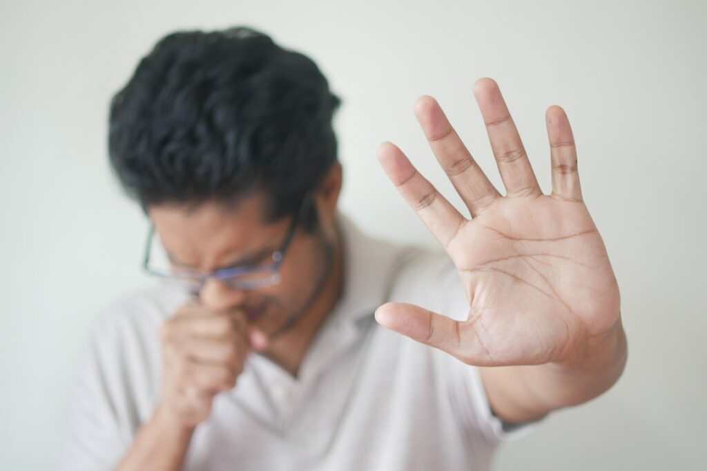 a man holding his hand up in front of his face
is it dangerous to sleep with a blocked nose