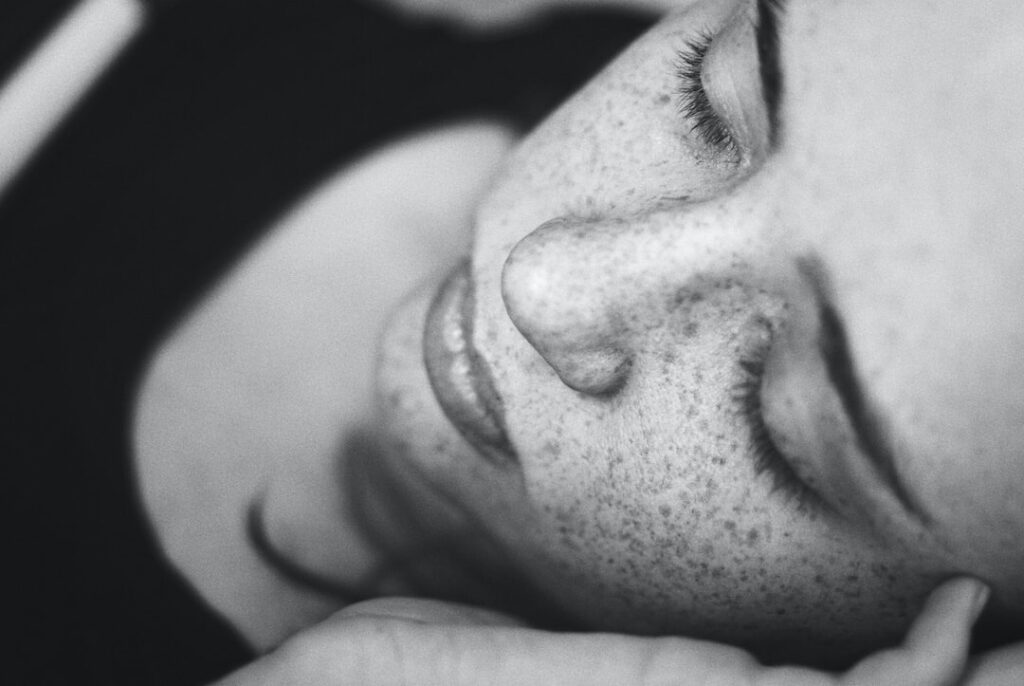 grayscale photo of woman's face with freckles
