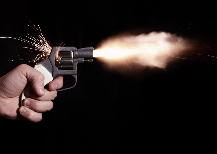 a person holding and firing a gun shot